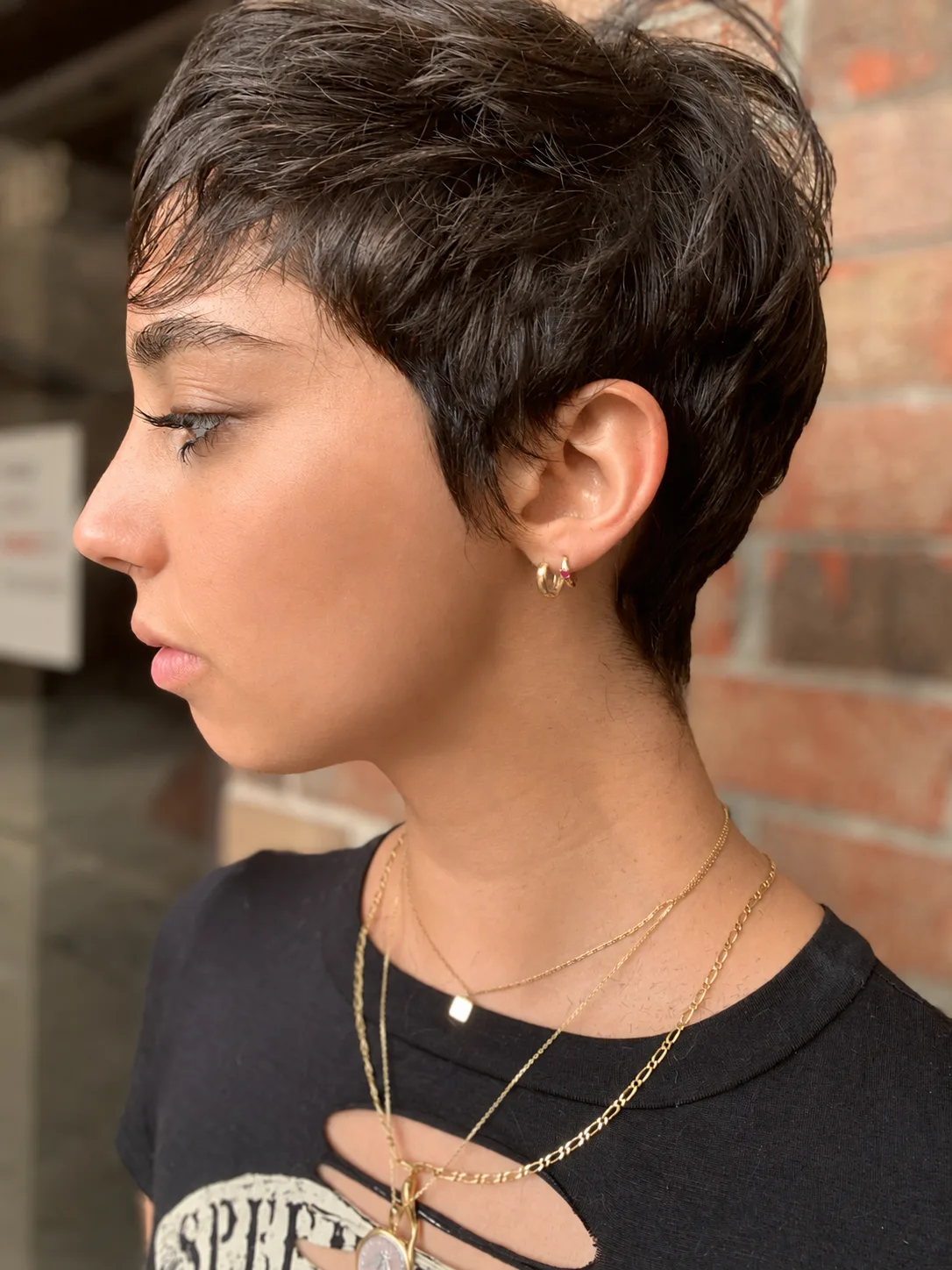 Side profile of a precision pixie cut with a clean outline and soft fringe