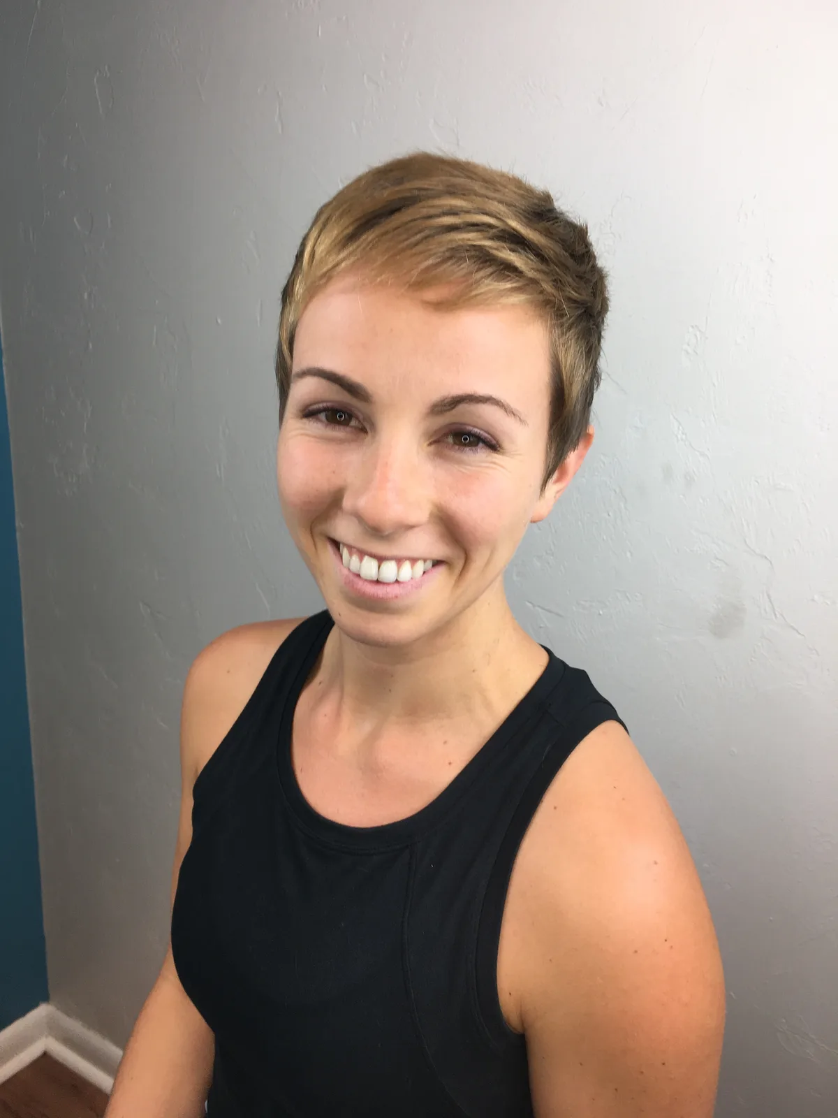Classic short pixie cut with blonde highlights on a smiling guest