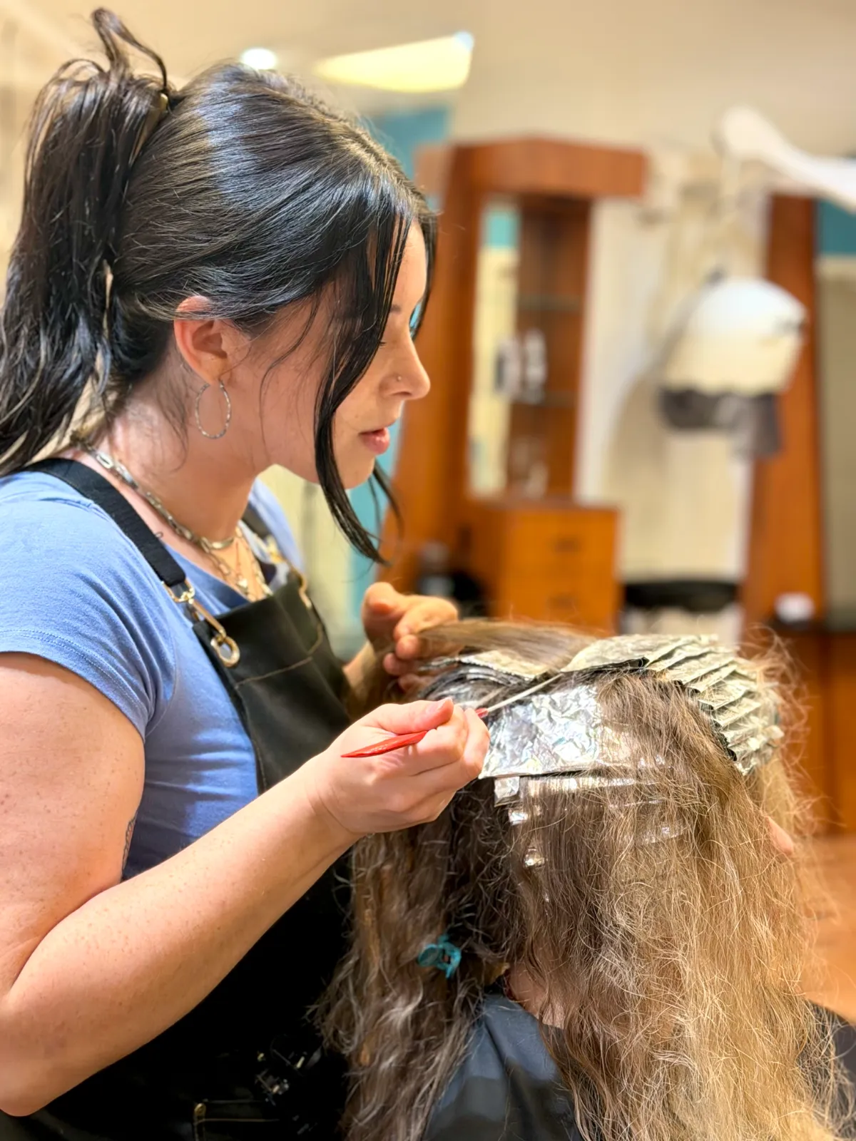 A Ciao Bella color specialist hand-painting blonde highlights onto sectioned hair
