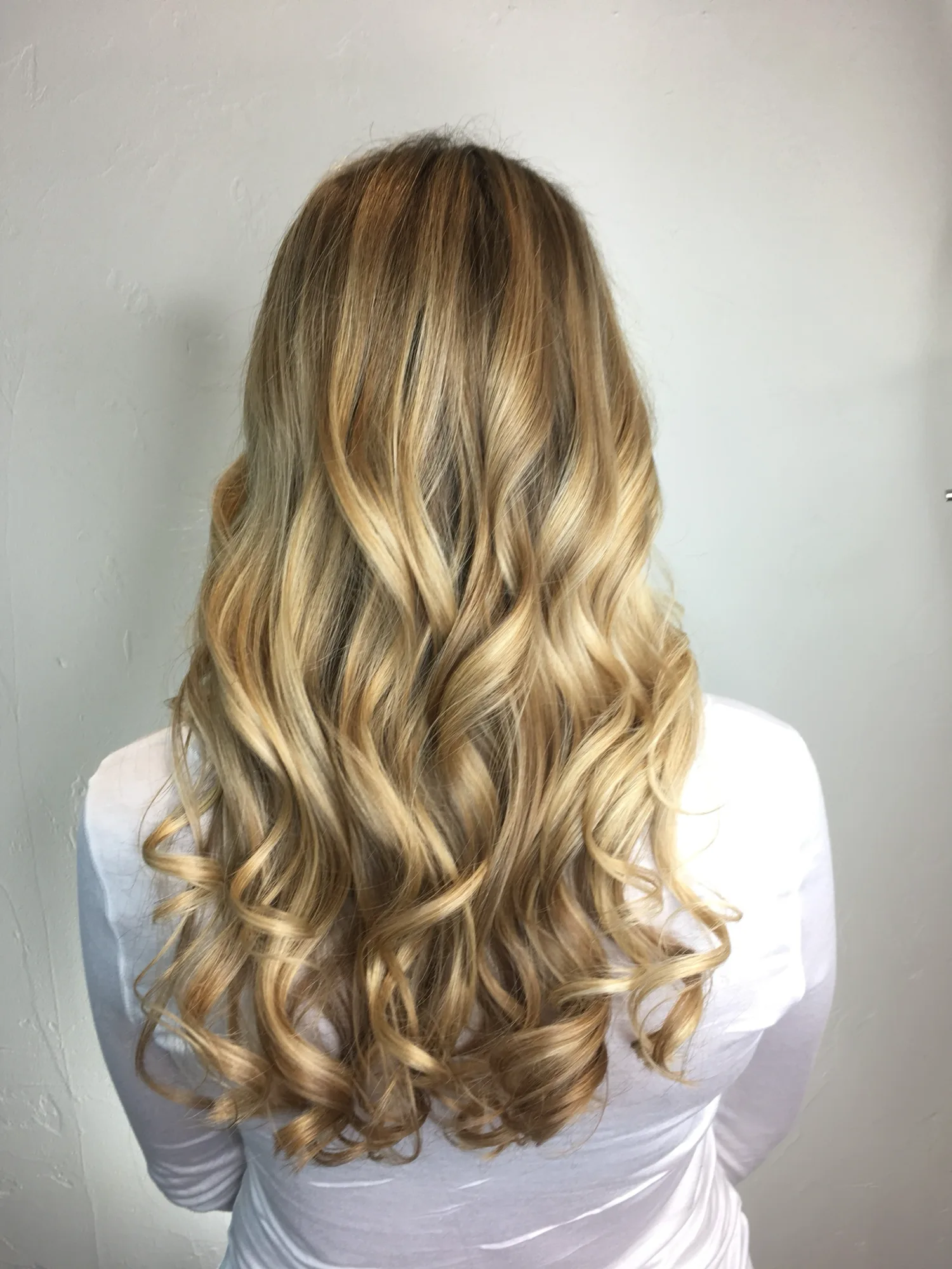 Golden blonde balayage with soft waves, roots melting to bright hand-painted ends