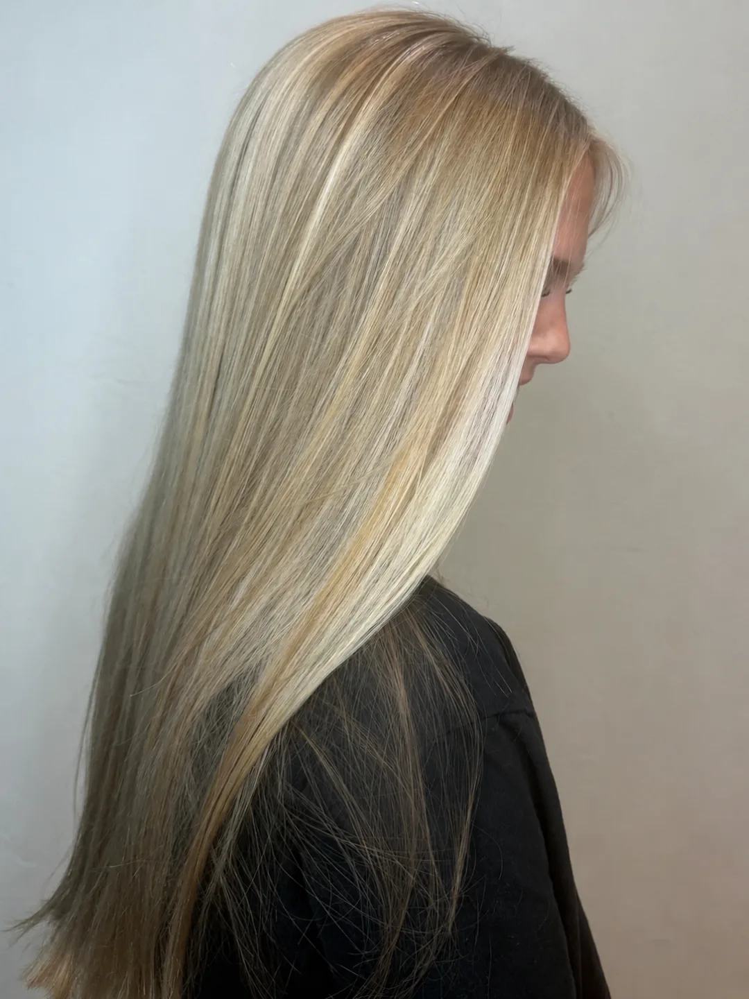 Long sleek blonde hair with dimensional highlights, cut to a clean blunt line, side profile