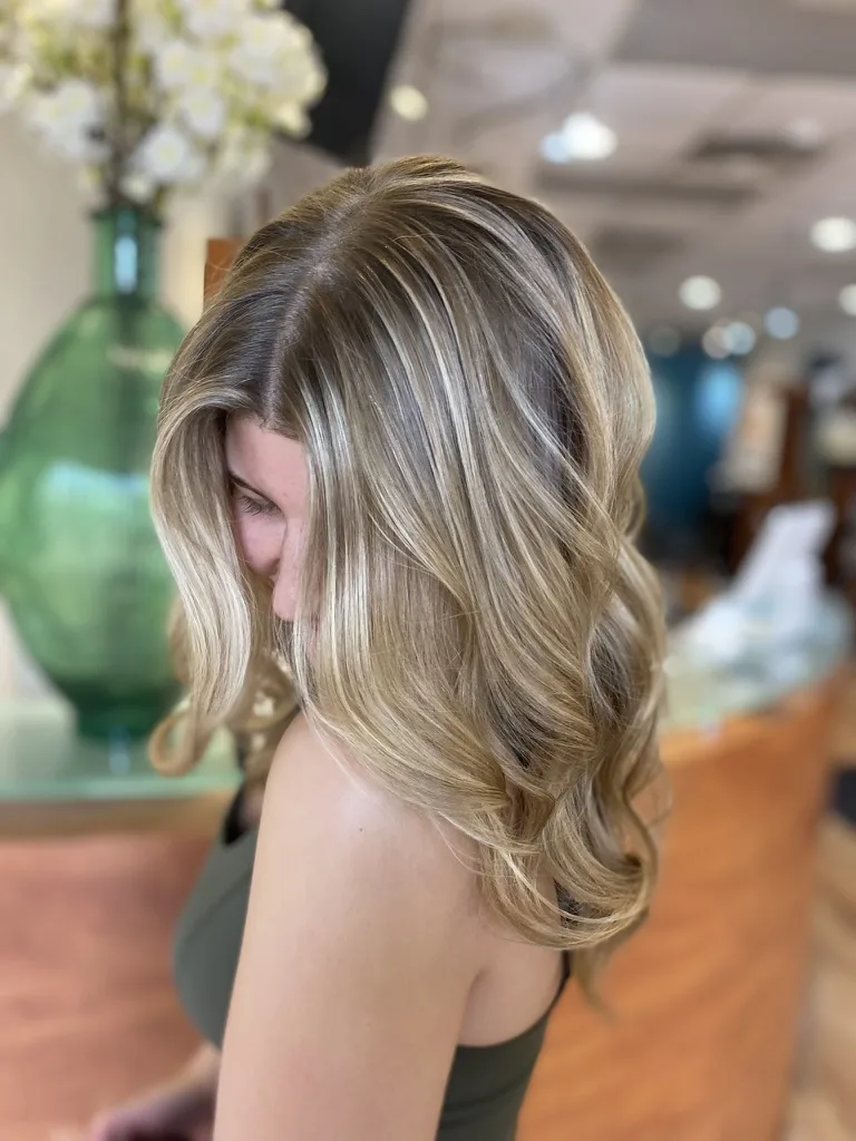 Long blonde hair with dimensional highlights and soft waves, cut and styled at Ciao Bella Salon
