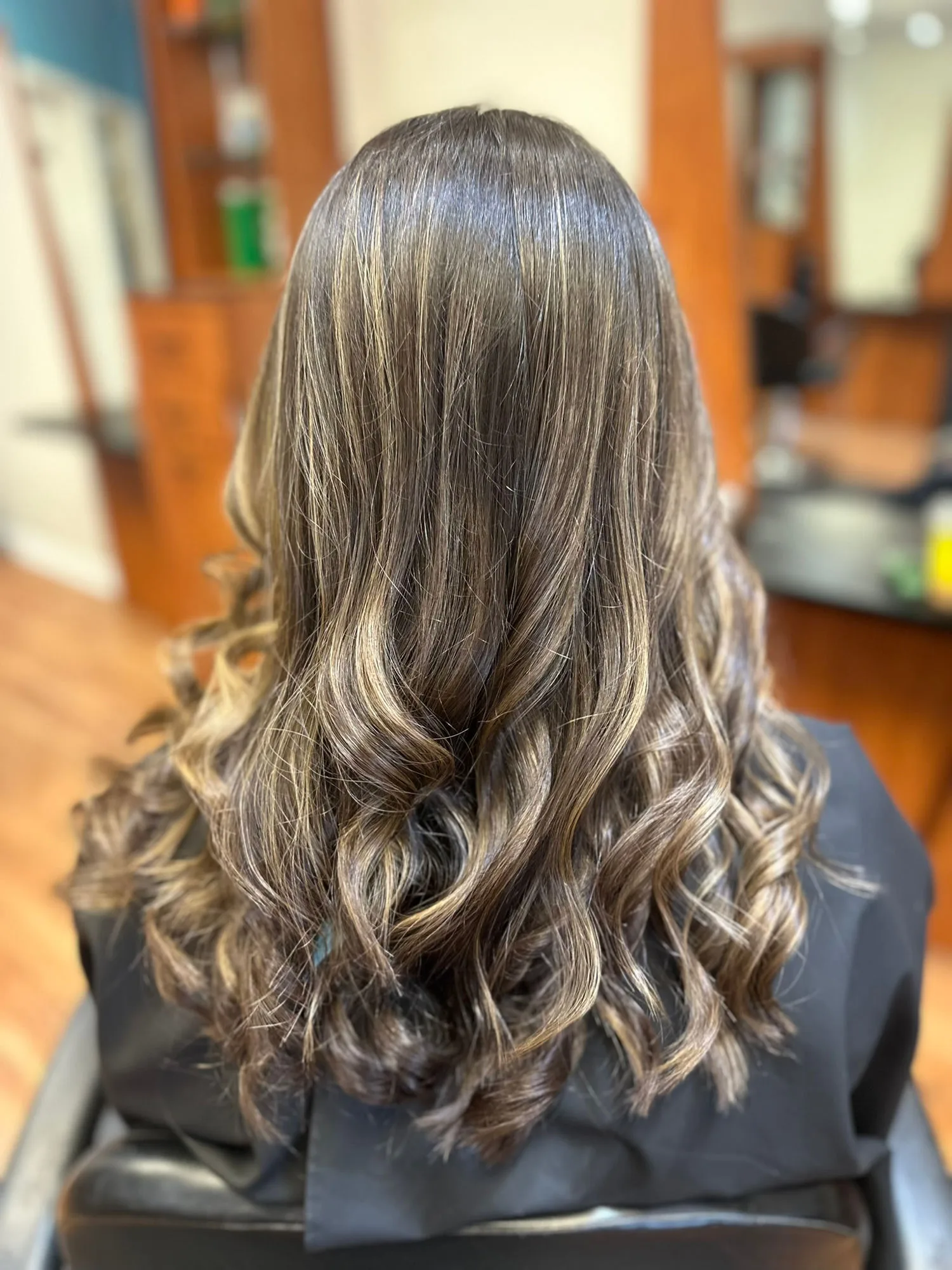Brunette balayage with soft hand-painted highlights, worn in loose curls