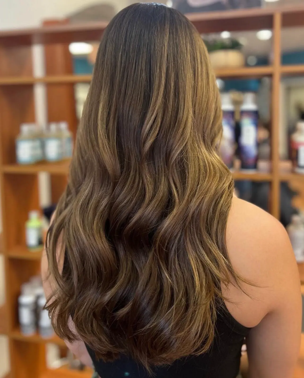 Brunette balayage with caramel dimension in soft waves, back view at Ciao Bella Salon