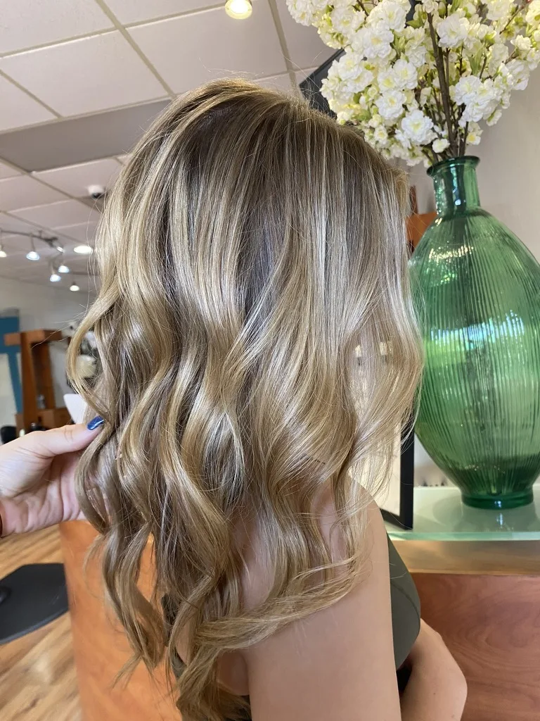 Mid-length caramel blonde hair with soft waves and face-framing layers