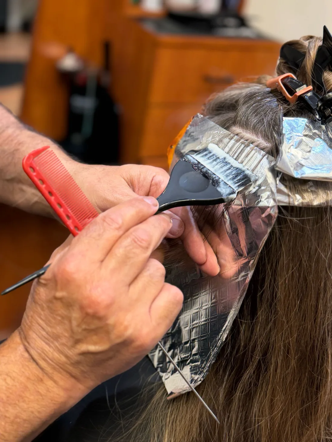 A stylist painting color onto a foiled section, close up