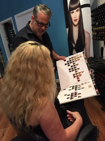 A Ciao Bella stylist walking a guest through a Goldwell color swatch book at a consultation