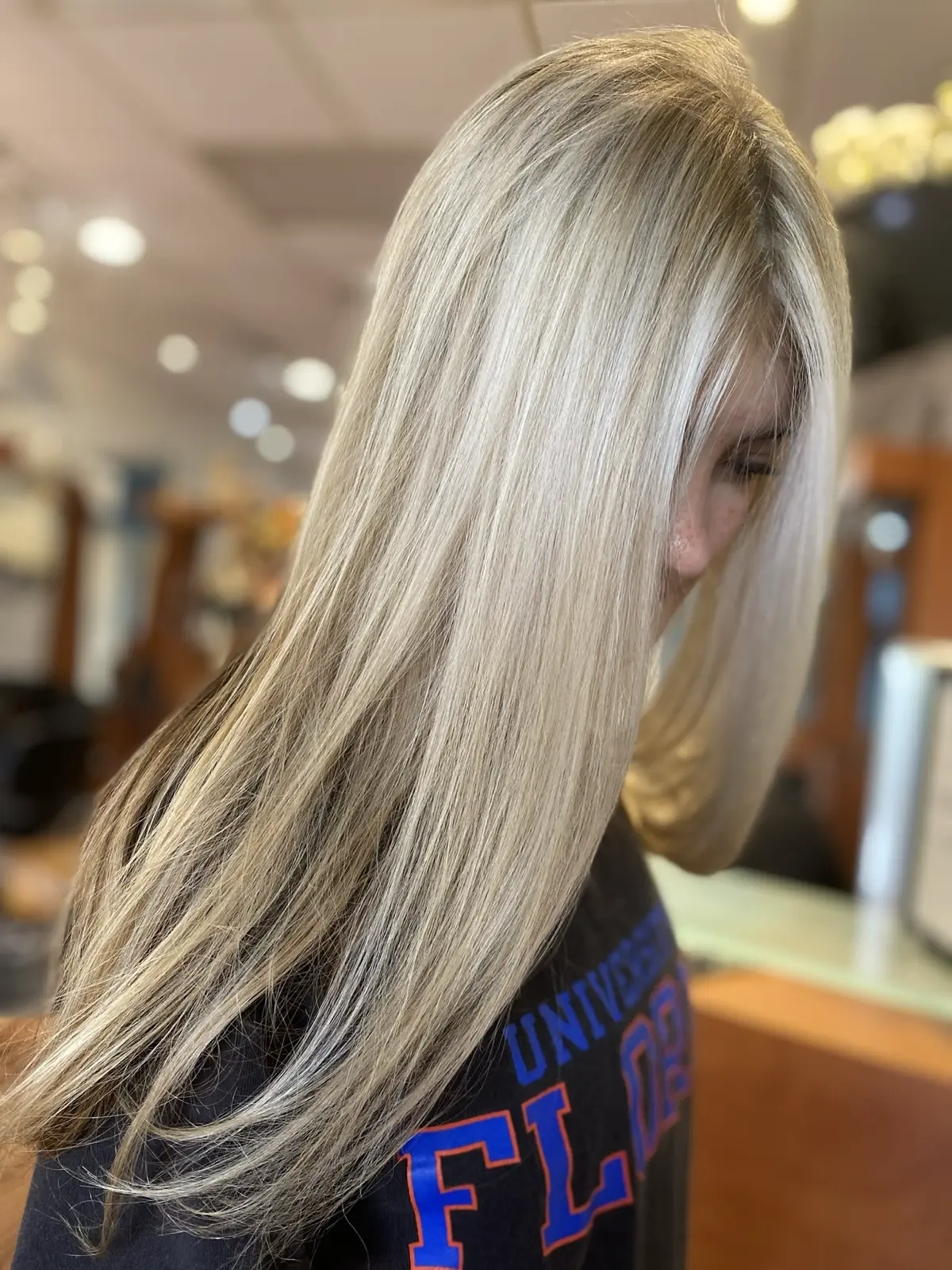 Bright platinum blonde highlights styled sleek, side profile at Ciao Bella Salon