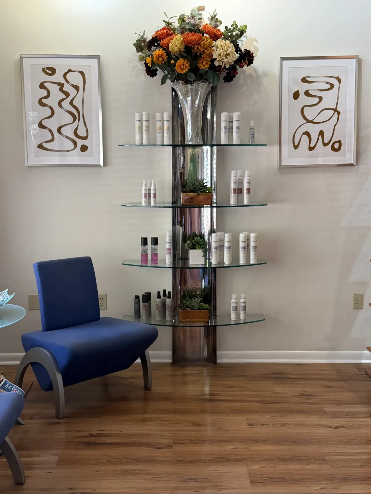 The Ciao Bella waiting area with a blue armchair, retail shelves, and fresh flowers, Downtown Gainesville